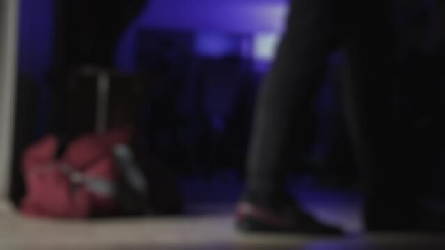 Football players change clothes in dark locker room before soccer match. Blurred. Men put on their sports uniforms strip, tracksuit in dressing room with blue lighting. Cloakroom. Shaky handheld shot
