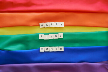 Happy Pride month concept. Happy pride month spelled with craft letters over lgbt rainbow flag