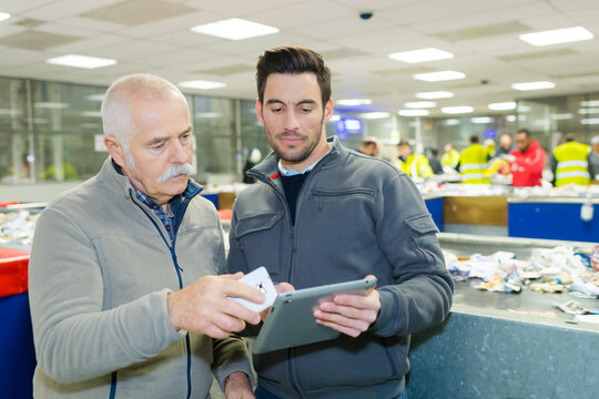 midsection of two workers holding tablet in industry