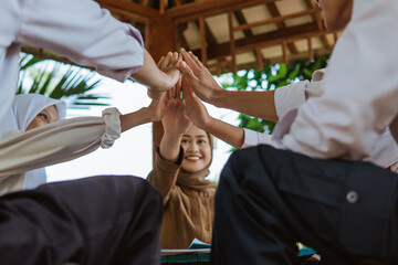 teacher and students put their palms together as a symbol of unity during outdoor class
