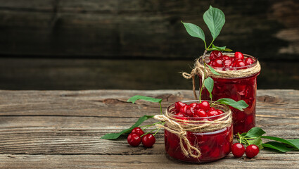 Jar of cherry jam and sour cherries. Berries cherry with syrup. Ripe ripe cherries. Sweet red cherries. Canned fruit on a wooden background