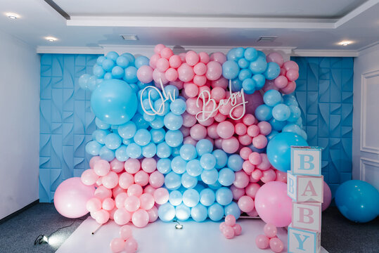Photo zone, arch with pink and blue balloons, cubes for gender party. Boy or girl. Know gender of unborn child. Happiness of parenthood. Background, wall with text oh baby. Baby Shower party decor.