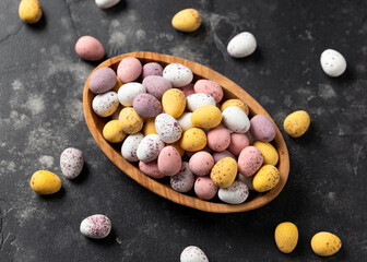 Easter mini eggs, chocolate candy in wooden bowl