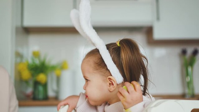 A cute girl eats an egg and plays with her mother. Happy Easter