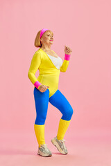 Fitness lover. Senior, aged, sporty woman in colorful sportswear training, posing against pink studio background. Concept of sportive lifestyle, retirement, health care, wellness. Ad