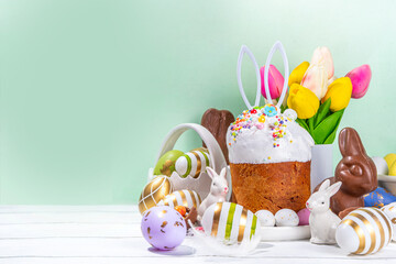 Tasty Glazed Easter cake with sugar decor, colorful eggs basket, ceramic rabbits and spring flower...