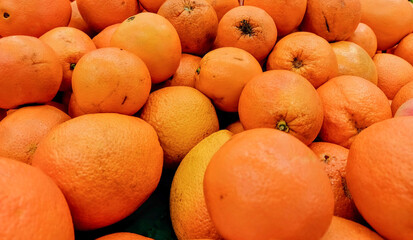 A lot of tangerines on the market. A background of fresh orange. Harvest of citrus fruits.