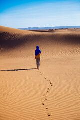 caucasian woman posing in blue waving textile in the sahara desert- footprints in sand dunes - Morocco