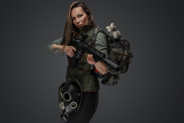 Studio shot of female mercenary carrying backpack and holding rifle.