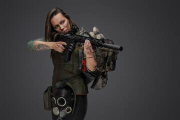 Studio shot of attacking female mercenary with backpack and rifle.