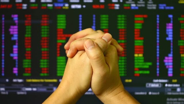 Man is praying  with stock exchange board background, in studio Chiangmai Thailand.
