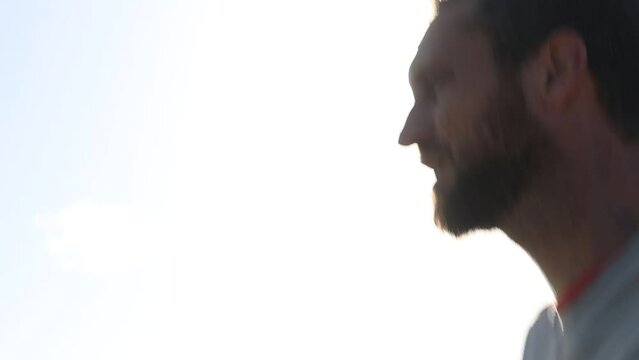 Looking up closeup follow shot of a male trail runner backlit with sun behind seen from the side profile. Athlete endurance training run exercise outdoor sports concept.