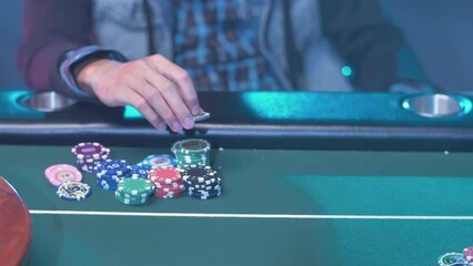 A professional poker player at the green table, moving his chips while waiting for his turn. Slow motion closeup shot. - Powered by Adobe