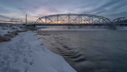Winter sunrise on the Bow River and a bridge in Cochrane, Alberta, Canada