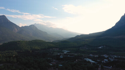 Mountains ridge with peaks behind the valley. Aerial panoramic view from drone. Top view of village in mountains.