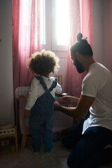 young black mother with fizzy hair and her little doughtier playing with educational toys in her room