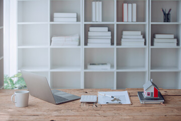 Young woman using mobile phone, laptop and calculator working on wooden table in office. Business and finance concept.