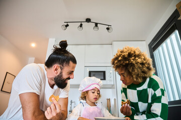 young interracial family with a black mother with fizzy hair backing some healthy pancakes in a bright kitchen
