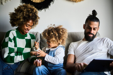 young interracial family with a black mother with fizzy hair spending time together at their sofa
