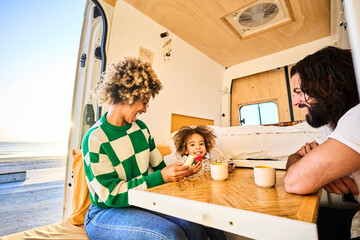 young interracial family spending quality time together with their daughter in a bright camper van