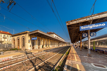 Fototapeta na wymiar Savigliano, Cuneo, Italy - Trenitalia railway station with tracks and platforms on the line between Turin and Savona with blue sky