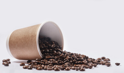 Bringing energy to your mornings. Studio shot of a tipped over paper cup filled with coffee beans against a white background.