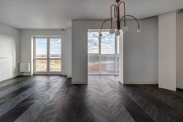 Empty apartment with large floor-to-floor window overlooking nature and blue sky with clouds