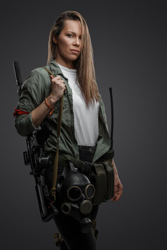 Portrait of killer woman with rifle in post apocalyptic style against gray background.