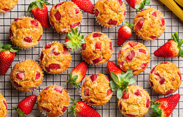 Strawberry banana muffins or cupcakes on a cooling rack with fresh fruits. Homemade sweet baked pastry. Beautiful summer food background. Top view.