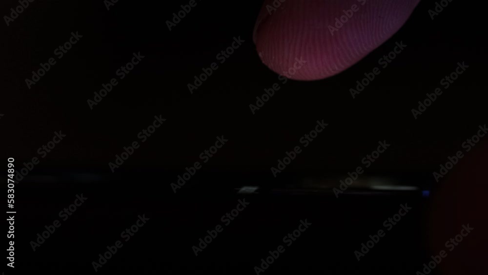 Poster finger scrolls smartphone screen in the dark illuminated by screen light. searching news and browsin