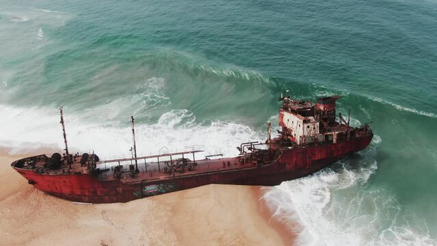waves crashing into the rusty shipwreck of an oil tanker