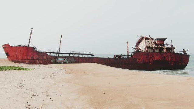 an abandoned and rusty shipwreck stranded on a beach in west africa