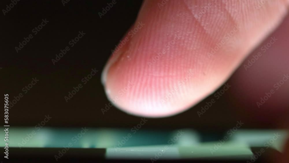 Poster finger scrolls smartphone screen in the dark illuminated by screen light. searching news and browsin
