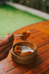 Men's hands hold with sticks fried shrimp with dim sum. A man eats Asian food. Stylish concept of fast food on the background of a wooden table