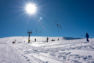 Fototapeta na wymiar People using ski lift on sunny winter day on ski resort