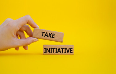 Take initiative symbol. Wooden blocks with words Take initiative. Businessman hand. Beautiful yellow background. Business and Take initiative concept. Copy space.