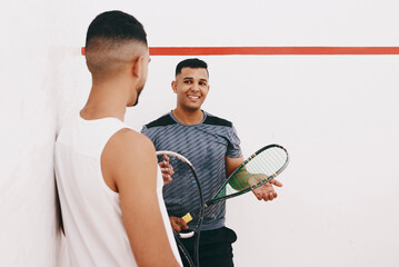 Friends first, team mates second. two young men chatting after playing a game of squash.
