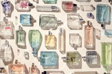 Perfume and eau de toilette bottles flatlay a lot, collection top view. Beautiful multicolored perfume bottles on a beige background, holiday gifts of choice. - obrazy, fototapety, plakaty