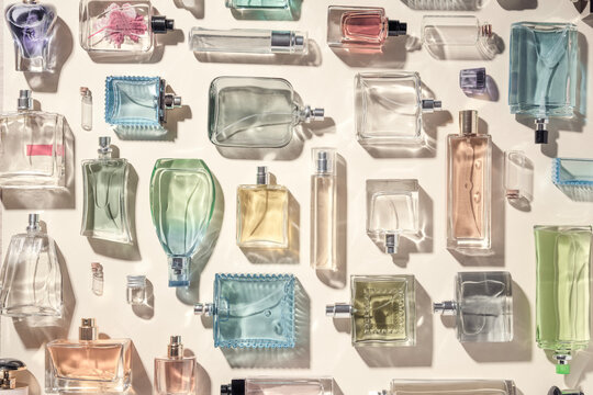 Perfume and eau de toilette bottles flatlay a lot, collection top view. Beautiful multicolored perfume bottles on a beige background, holiday gifts of choice.