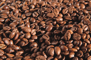 Coffee beans background. Texture of coffee beans close up. Dark brown roasted coffee is spinning. Abundance. Concept for coffee product advertising. Selective Focus. Border design with copy space