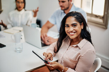 You wont find a more collaborative team. a young businesswoman using a digital tablet during a meeting in a modern office.