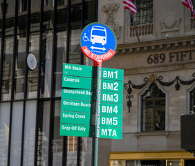 A Fifth Avenue bus stop sign in midtoswn manhattan showing various bus lines.