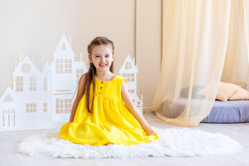 Little cute girl in yellow dress plays in the bright children's room. Funny cute little girl having...