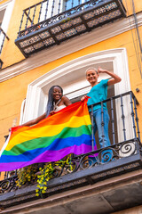 Obraz na płótnie Canvas Lesbian girl couples with lgbt flag on balcony at home party, waving, LGBT pride