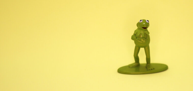 Kermit the Frog. Character from the Muppets and Sesame Street. Talking frog. Metallic figure on a yellow background. Puppet. Miss Piggy's friend. Presenter of television shows and movies. Ren&eacute;. Rene.