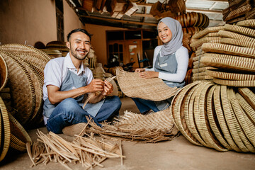 Obraz na płótnie Canvas portrait of two handicraft worker is weaving traditional bamboo products in his workshop
