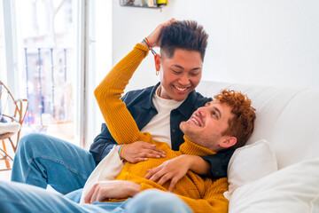 Fototapeta premium Beautiful gay couple being romantic at home on the sofa, hugging, lgbt concept