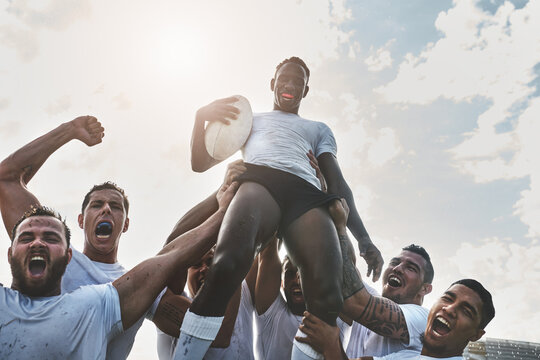 Winners all the way. Portrait of a group of cheerful young rugby players celebrating their win by lifting one of their teammates.