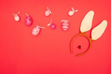 Bunny ears and Easter eggs on a red backdrop with plenty of copy space for Easter greetings