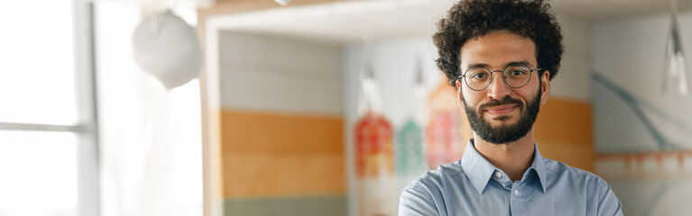 Portrait of smiling businessman standing in modern office on colleagues background